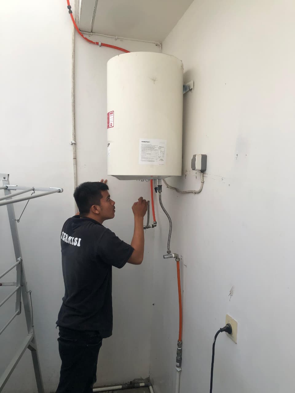 Teknisi profesional sedang memeriksa dan memperbaiki water heater di dalam rumah, lingkungan kamar mandi modern bersih